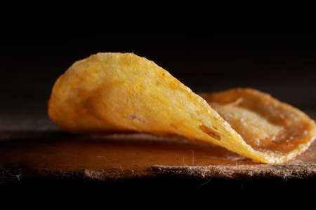 macro photo of chips on a wooden table, a slice of fried potatoes, beer snacks, blurred backgroundの写真素材