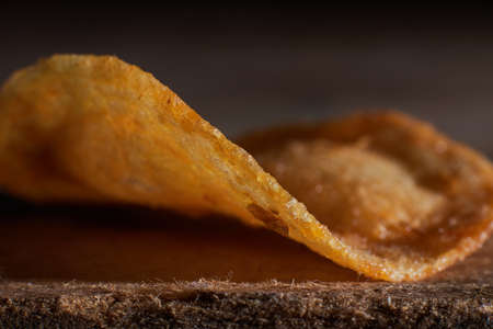 macro photo of chips on a wooden table, a slice of fried potatoes, beer snacks, blurred backgroundの写真素材