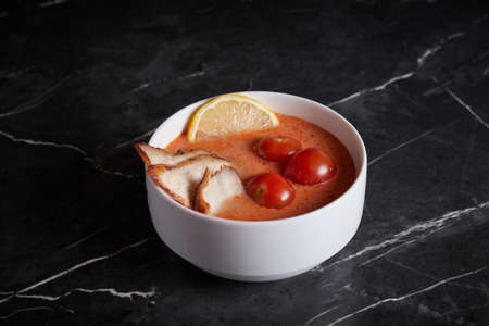 asian soup with meat and seafood, plate close-up on a dark background, vegetablesの写真素材