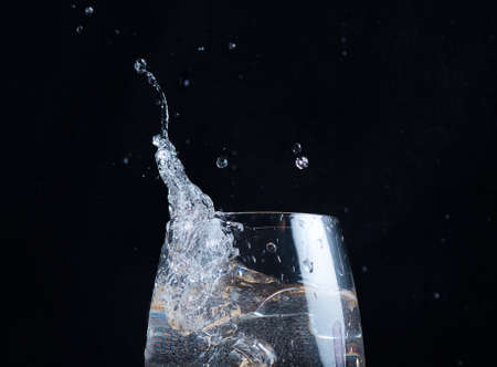 In clear water in a glass, splashes and waves pour over a blurry backgroundの写真素材