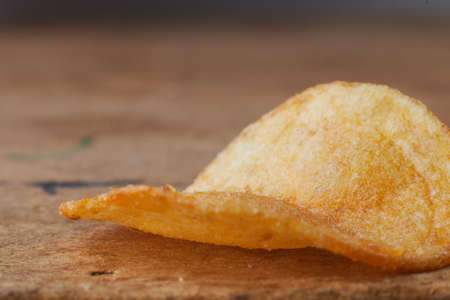 macro photo of chips on a wooden table, a slice of fried potatoes, beer snacks, blurred backgroundの写真素材