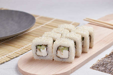 a portion of rolls on a stand, japanese food, sushi on the table, chinese chopsticks, light backgroundの写真素材