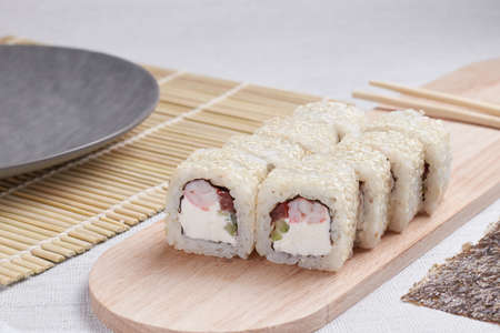a portion of rolls on a stand, japanese food, sushi on the table, chinese chopsticks, light backgroundの写真素材