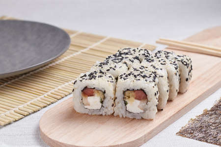 a portion of rolls on a stand, japanese food, sushi on the table, chinese chopsticks, light backgroundの写真素材