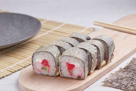 a portion of rolls on a stand, japanese food, sushi on the table, chinese chopsticks, light backgroundの写真素材