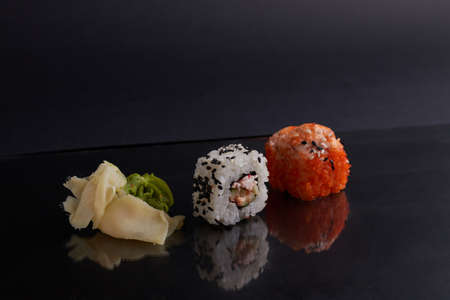 several different rolls on the table, asian food, side view, dark background, sushi, ginger and wasabiの写真素材