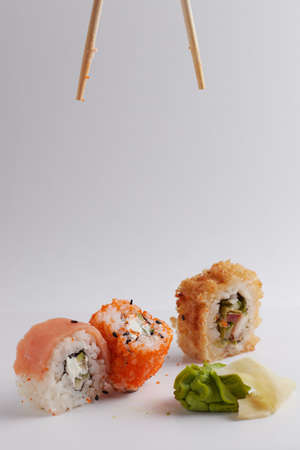 hand and chinese chopsticks, roll falls on the table above other sushi, portion of asian food, rollsの写真素材