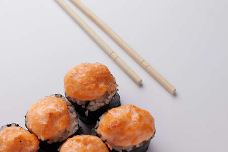 a portion of rolls on a stand, japanese food, sushi on the table, chinese chopsticks, light backgroundの写真素材
