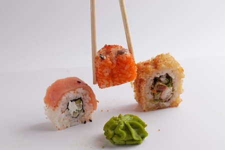 a hand and Chinese chopsticks holds a roll over other sushi, a portion of Asian food, rollsの写真素材