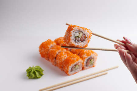 a hand and Chinese chopsticks holds a roll over other sushi, a portion of Asian food, rollsの写真素材