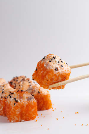 a hand and Chinese chopsticks holds a roll over other sushi, a portion of Asian food, rollsの写真素材
