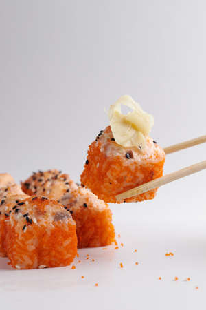 a hand and Chinese chopsticks holds a roll over other sushi, a portion of Asian food, rollsの写真素材