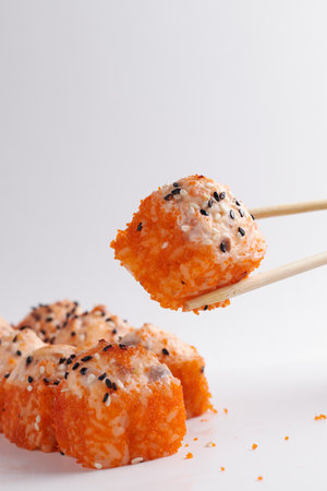 a hand and Chinese chopsticks holds a roll over other sushi, a portion of Asian food, rollsの写真素材