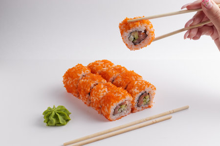 a hand and Chinese chopsticks holds a roll over other sushi, a portion of Asian food, rollsの写真素材