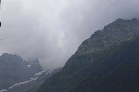 fog in the mountains, green forest and coniferous trees, slopes and ravines, landscape at duskの写真素材