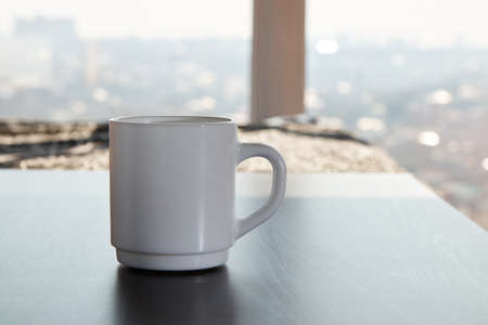 White mug for tea and coffee in on the ebony table, light background close-upの写真素材
