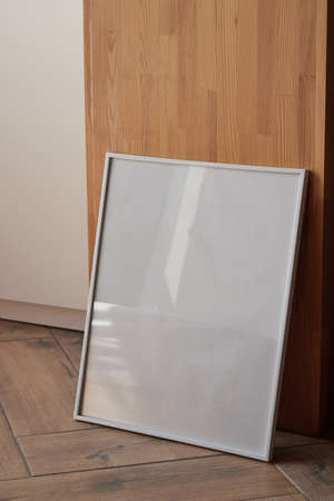 Large white photo frame on the floor, mockup, poster against the wall, dark background