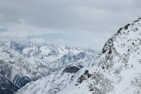 mountains in snow, winter mountain landscape, gloomy sky and fog, rocks in foregroundの写真素材