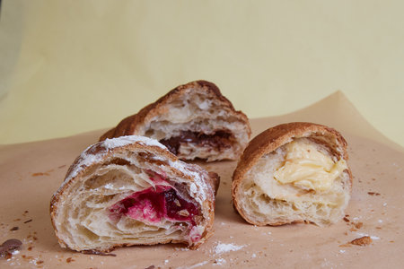 fresh croissants on table, dessert with powdered sugar and fruit filling, monochromatic background, close-upの写真素材