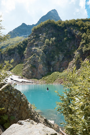 Lake in the mountains, rocks and stones, reflection of the sky and clouds in the water, alpine meadows and forest on the mountainsideの写真素材