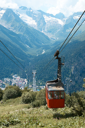 Cable car in the mountains, grass and mountains with glaciers, alpine meadows, village in the mountainsの写真素材