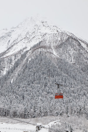 pendulum lift in mountains, cable car, red cabin, winter, snow on slopes and her on forest,の写真素材