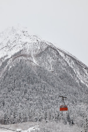 pendulum lift in mountains, cable car, red cabin, winter, snow on slopes and her on forest,の写真素材