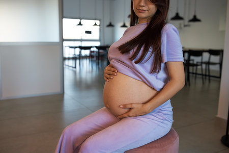 a pregnant girl sits on ottoman, in spacious room, meeting roomの写真素材
