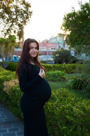 pregnant girl holding her belly, around flowers and plants, in gardenの写真素材