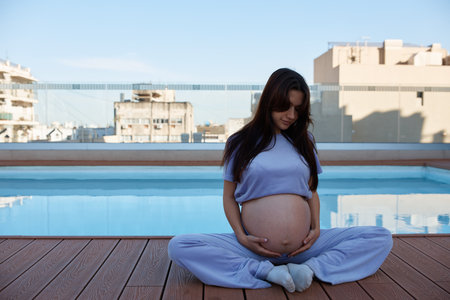 pregnant girl near pool, holding her stomach, close-upの写真素材