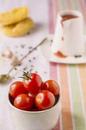 Red cherry tomatoes in a white ceramic plate on linen napkin.Background.Selective focusの写真素材