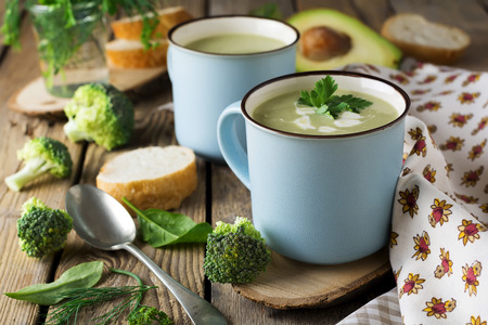 soup of broccoli and avocado ceramic blue cup on the old wooden table background.Selective focus.の写真素材