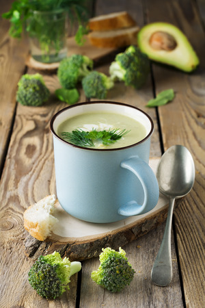 soup of broccoli and avocado ceramic blue cup on the old wooden table background.Selective focus.の写真素材