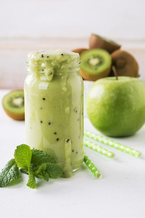Fresh homemade kiwi juice in a glass jar on white background.の写真素材