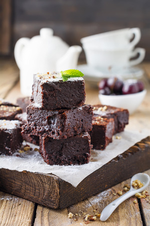Chocolate brownies with powdered sugar and cherries on a dark wooden background. Selective focus.の写真素材