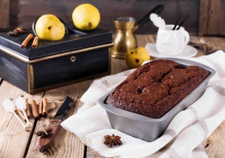Chocolate cake with pears and cinnamon on old wooden background. Selective focus.の写真素材