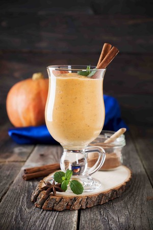 Pumpkin smoothie with cinnamon and granola on the old wooden background. Selective focus.の写真素材