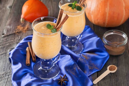Pumpkin smoothie with cinnamon and granola on the old wooden background. Selective focus.の写真素材
