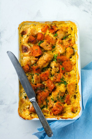 Baked pumpkin with chicken, spices and cream sauce in a white ceramic form on a light background. Selective focus.Top view.の写真素材