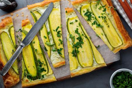 Tart with zucchini, ricotta cheese and parsley on a dark concrete background. Top view. Selective focus.の写真素材