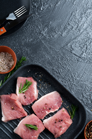 Meat. Raw pieces of pork with rosemary and pepper on a black background. Selective focus. Top view. Place for text.の写真素材