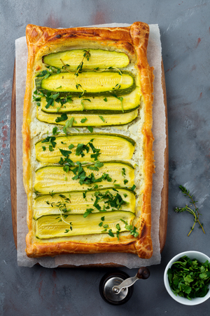 Tart with zucchini, ricotta cheese and parsley on a dark concrete background. Top view. Selective focus.の写真素材