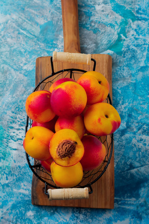 Fresh juicy fruit nectarines in  metal grid on blue concrete background. Selective focus. Top view. Rustic style.の写真素材