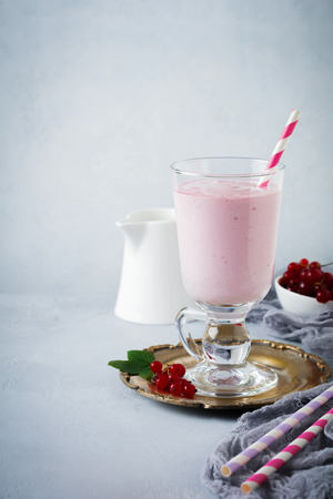 Red currant yoghurt smoothies, milkshake in a glass cup on a gray concrete background. Selective focus. Copy space.の写真素材