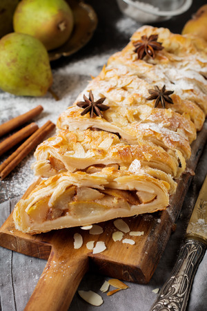 Homemade pear strudel, decorated with almonds, anise and powdered sugar on a rustic background. Selective focus. Top view.の写真素材