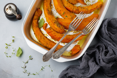 Fried pumpkin slices with herbs and pepper, olive oil on a gray concrete or stone background. Selective focus.Top view.の写真素材