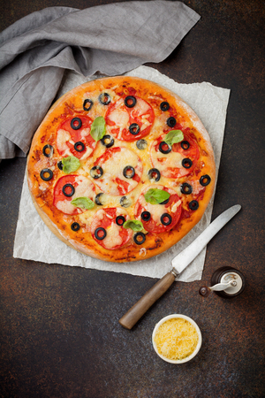 Pizza margarita with tomatoes, mazarella and slices of olives on a dark concrete or stone background. Traditional Italian cuisine. Selective focus. Top view.の写真素材