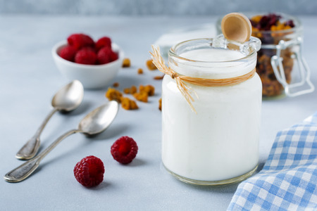 Fresh natural yogurt in a glass jar on  gray concrete or stone background.Healthy foodfor breakfast. Milk dairy product. Selective focus.の写真素材