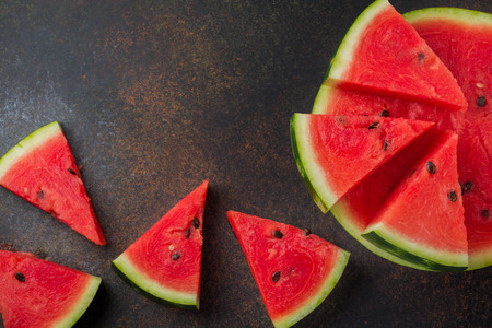 Fresh raw watermelon cut into pieces on  gray stone background. Selective focus. Top view. Copy space.の写真素材
