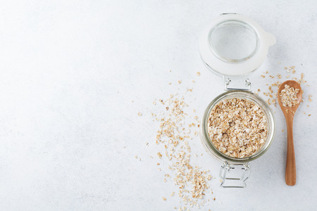 Raw oat flakes in a glass jar on a light background.Oatmeal. Selective focus.Top view. Copy space.の写真素材